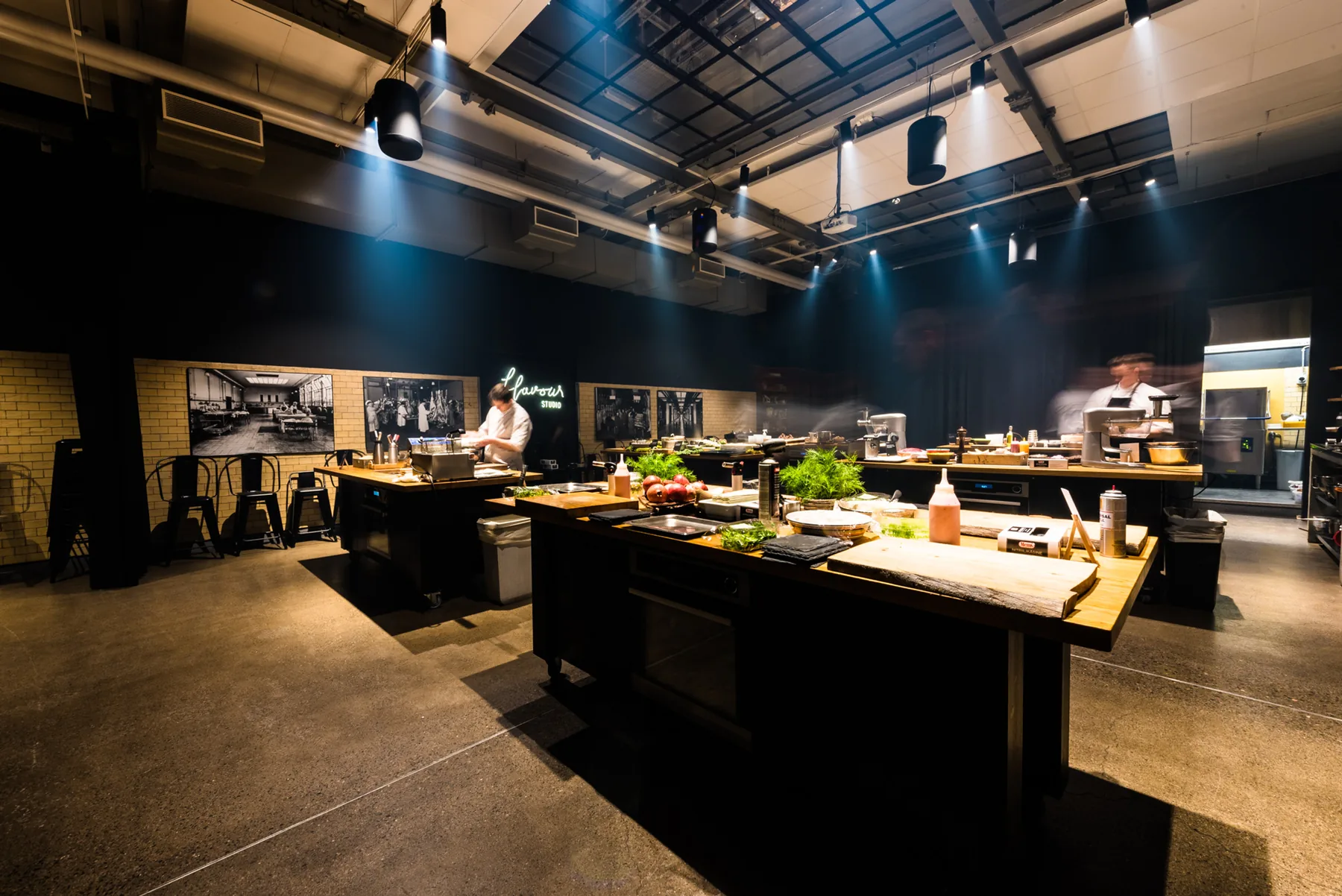 The Flavour Studio room seen from above: cooking stations, the counter and the neon sign.