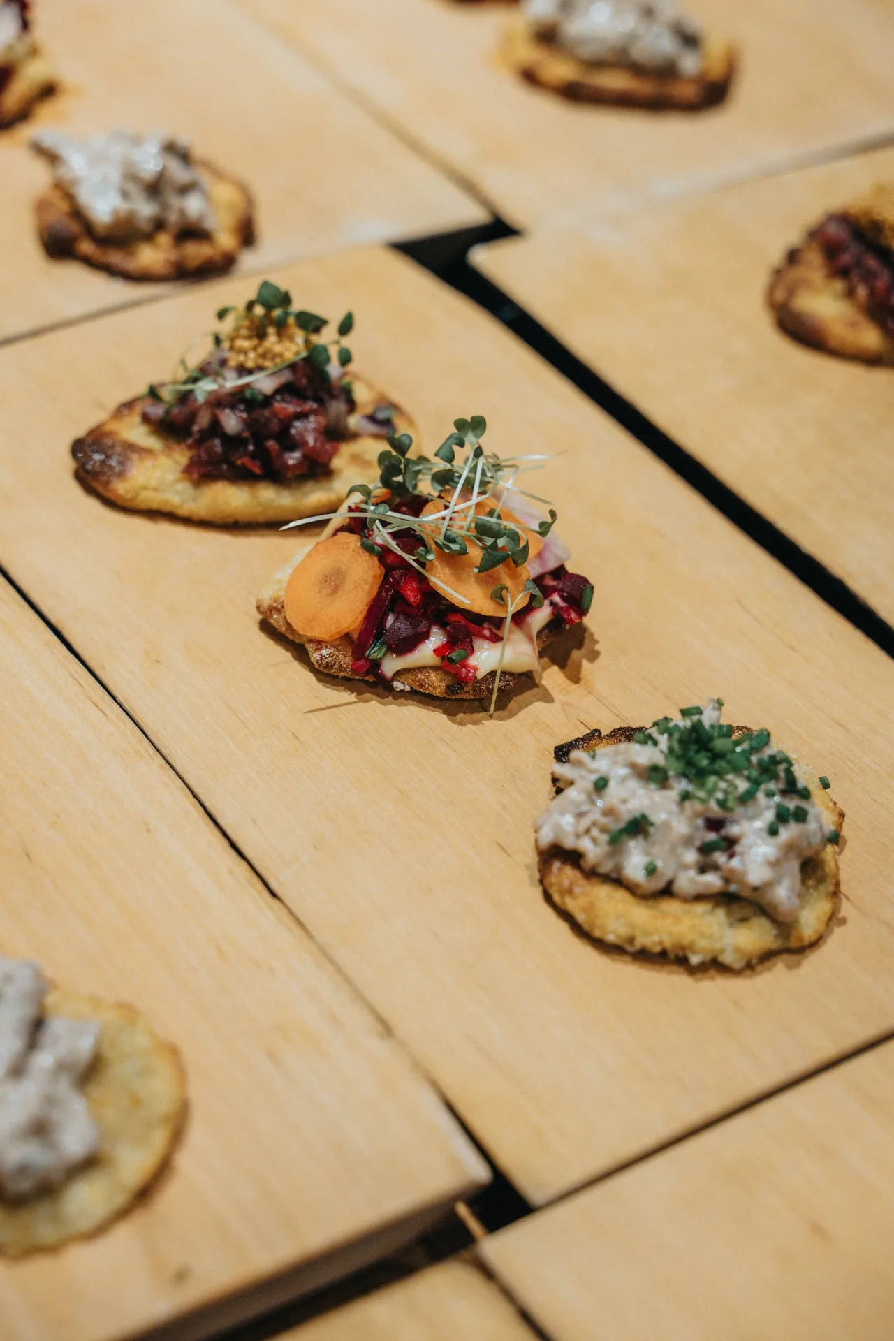 Blinis with toppings on wooden boards.